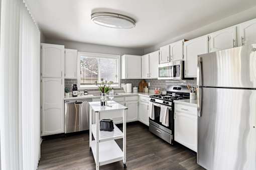 Open-concept kitchen with white cabinets and stainless steel fridge at Ashford at Geneva – pet-friendly apartments in Geneva, IL