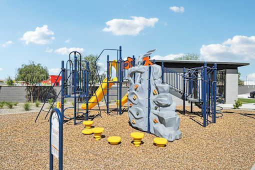 A playground with a blue and yellow slide and climbing structure.