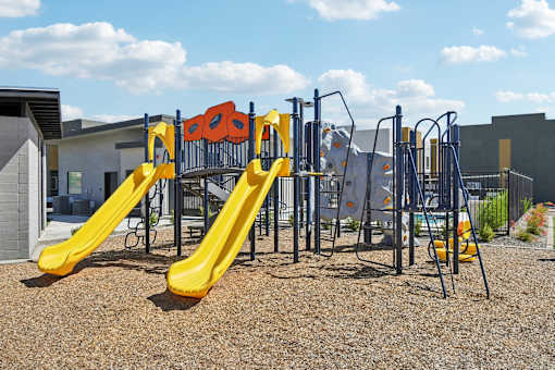 A playground with a yellow slide and a blue and yellow climbing frame.
