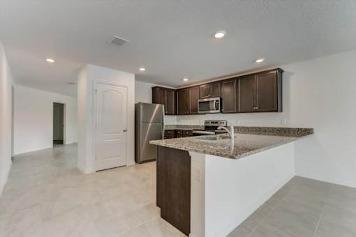 a kitchen with an island with granite countertops and a stainless steel refrigerator