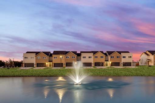 A fountain in the middle of a lake in front of a building.