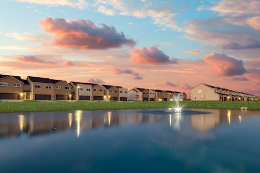 A row of houses are reflected in the water in front of them.