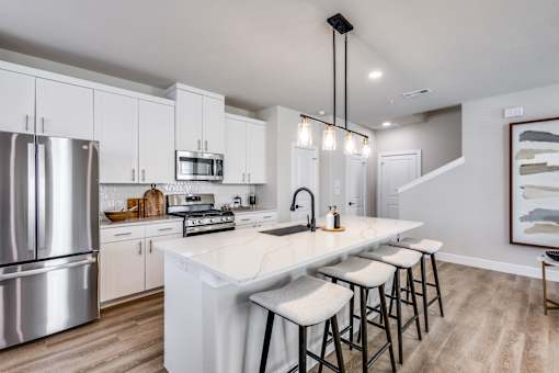 A modern kitchen with a white island and stainless steel appliances.