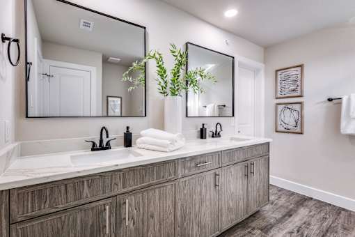 A bathroom with a large mirror and wooden cabinets.