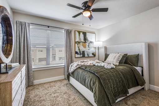 A bedroom with a bed, dresser, and a ceiling fan.