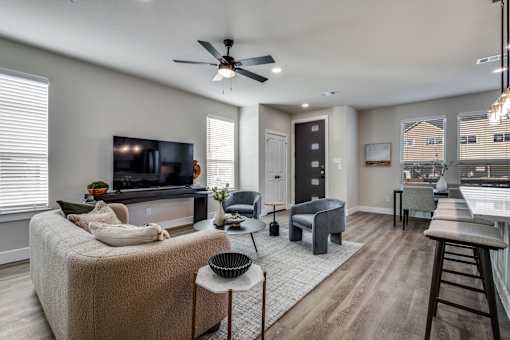 A living room with a couch, a television, and a ceiling fan.