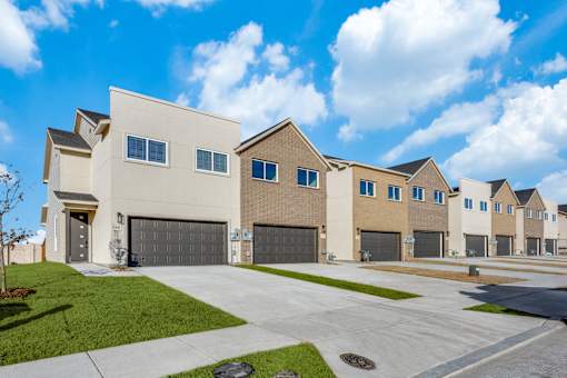 A row of modern houses with garages and driveways.