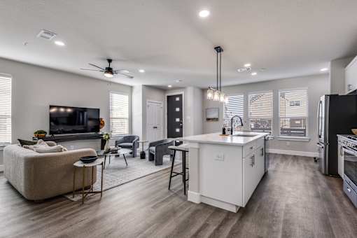 A modern kitchen with a white island and a living room with a sofa.