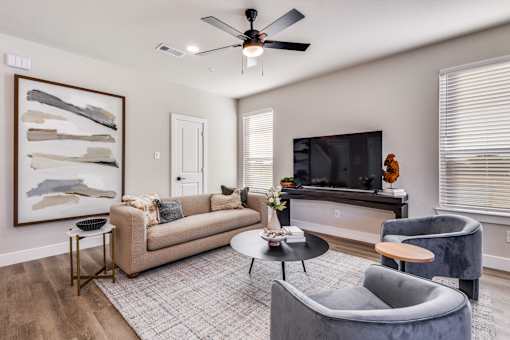 A living room with a grey couch, a black television, and a painting on the wall.