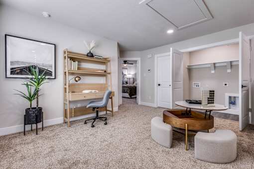 A room with a desk, chairs, and a plant.