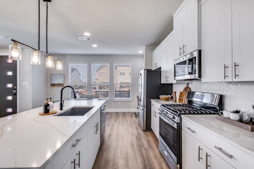 A modern kitchen with white cabinets and a black stove top oven.