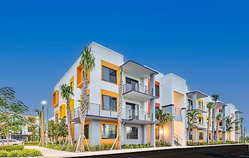 Modern exterior of Gateway Luxury Apartments in Pompano Beach, showcasing sleek architecture and palm trees.