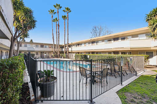 A pool surrounded by a black fence with a building in the background.