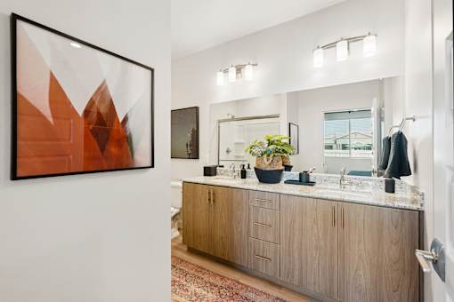 A bathroom with a wooden vanity and a large abstract painting on the wall.