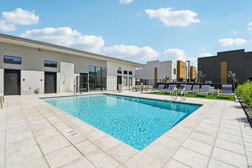 A pool surrounded by a patio and a building.