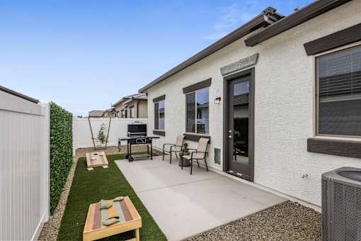 A patio with a table and chairs is surrounded by a white fence.