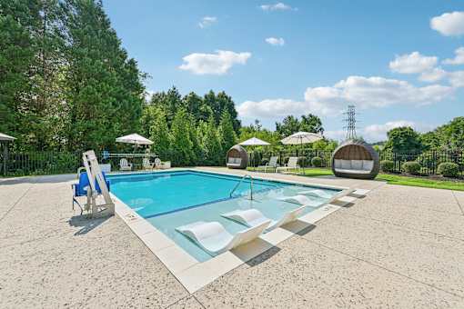 A large resort-style swimming pool at Hawks Landing in Hickory NC surrounded by trees and lounge chairs