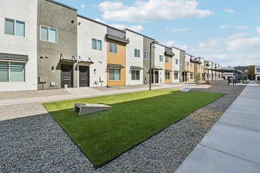 A row of modern townhouses with a grassy area in the foreground.