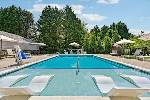 A large Hawks Landing swimming pool in Hickory NC with white lounge chairs and umbrellas