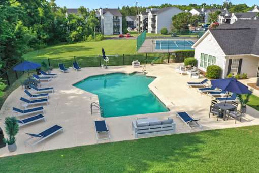 A large outdoor swimming pool surrounded by lounge chairs and umbrellas.