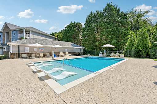 A bright Hawks Landing pool area in Hickory NC lined with white lounge chairs and umbrellas