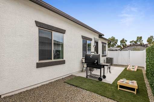 A small white house with a black chair and table outside.