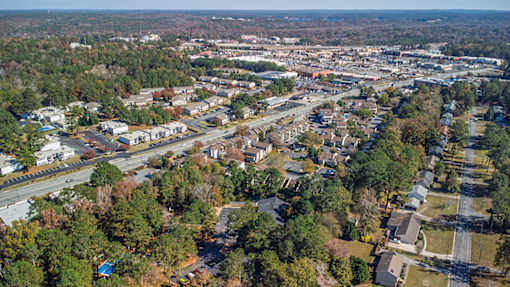 A bird's eye view of a suburban area with roads, houses, and trees.