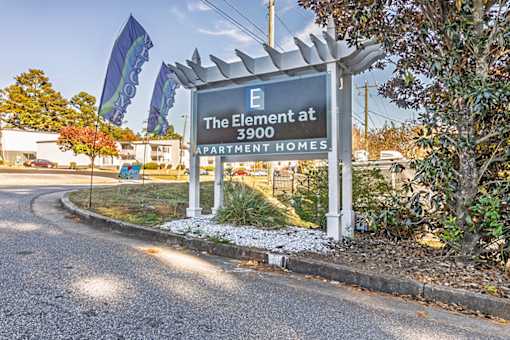 A sign for The Element at 3900 Apartment Homes is displayed in front of a building.