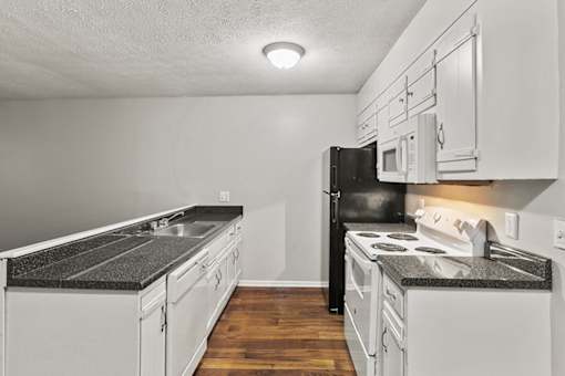 A kitchen with black appliances and white cabinets.