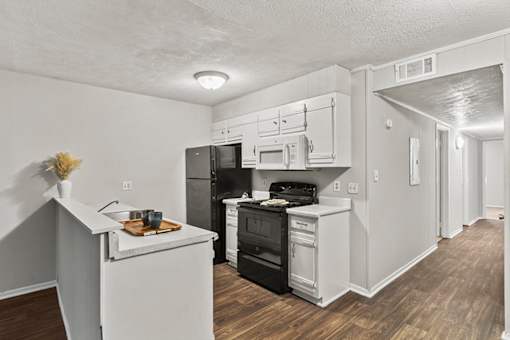 A kitchen with black appliances and white cabinets.