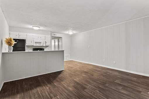 A kitchen with white cabinets and a wooden floor.