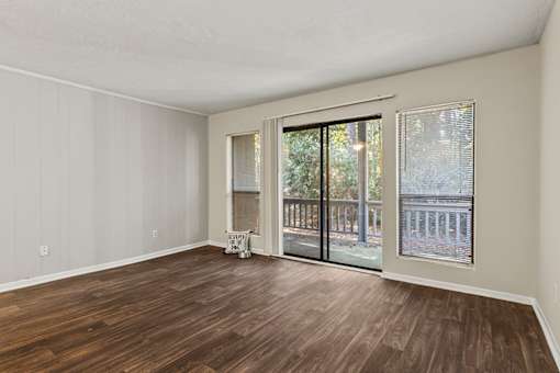 A room with wooden flooring and a sliding glass door leading to a balcony.