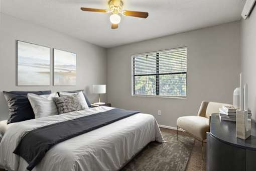 A bedroom with a bed, chair, and window.