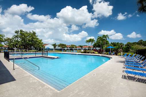 A large outdoor swimming pool surrounded by blue lounge chairs.