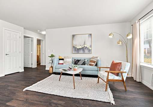 A living room with a grey couch, a white coffee table, and a painting on the wall.