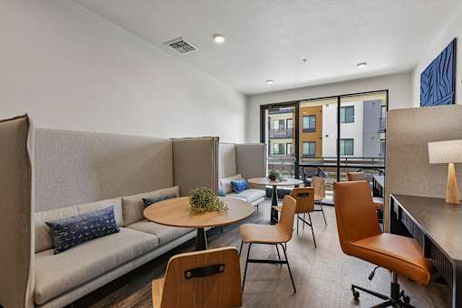 A modern living room with a grey sofa, wooden chairs and a round table.