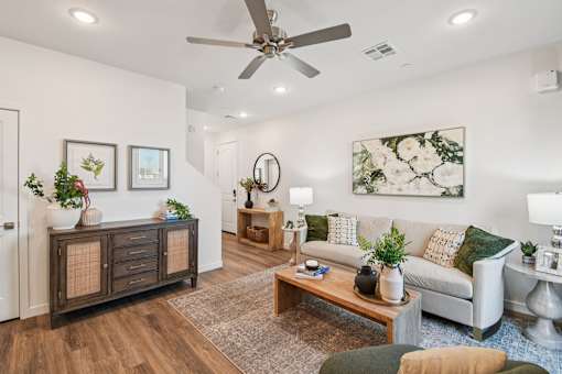 A living room with a white couch, a wooden coffee table, and a ceiling fan.