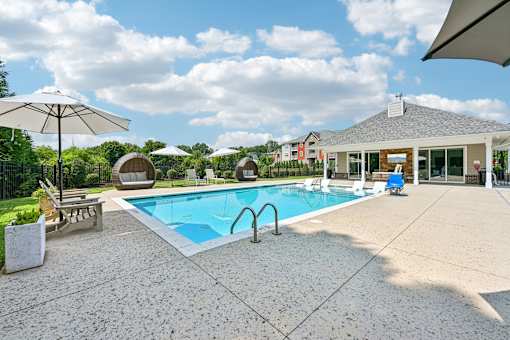 A pool with a sun umbrella and a bench.