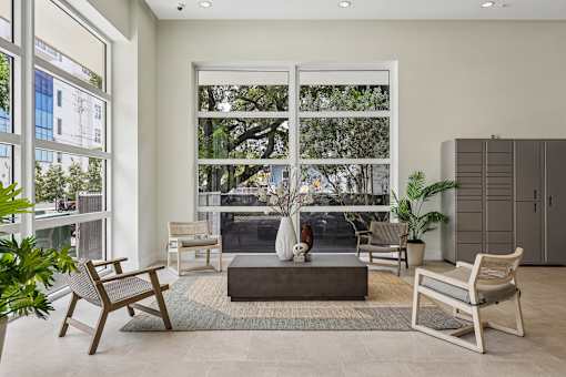 A living room with a large window and a view of trees and a building outside.