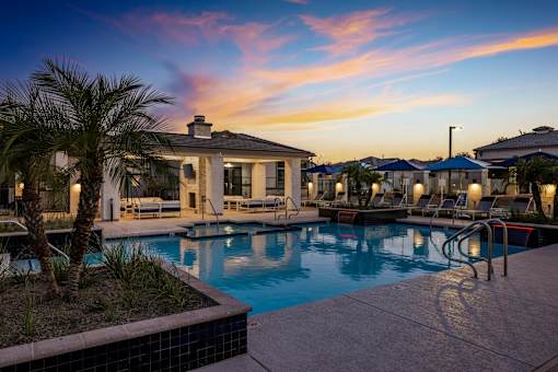 A pool surrounded by palm trees and lounge chairs.