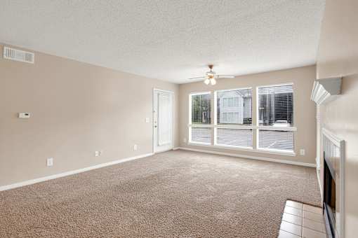 A room with a carpeted floor and a ceiling fan.