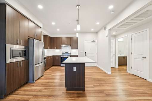 Open apartment kitchen with modern cabinetry, center island and hardwood-style flooring at Santana Terrace