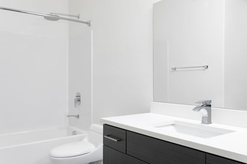 A white bathroom with a toilet, sink, and mirror.