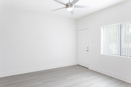 A room with a ceiling fan and a door.