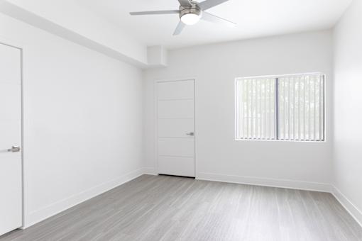 A room with a ceiling fan and a window with blinds.