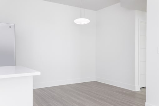 A white room with a light hanging from the ceiling and a white counter.