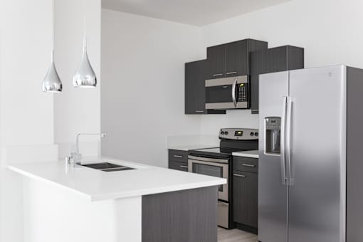 A modern kitchen with a white countertop and stainless steel appliances.