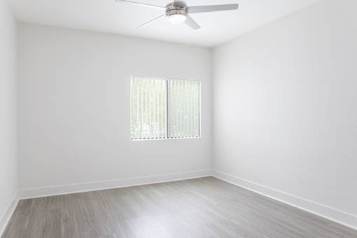 A room with a ceiling fan and a window with blinds.