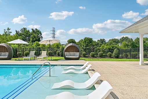A refreshing swimming pool at Hawks Landing in Hickory NC surrounded by white loungers and umbrellas