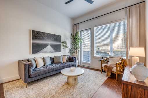 A living room with a grey couch, a white coffee table, and a painting on the wall.